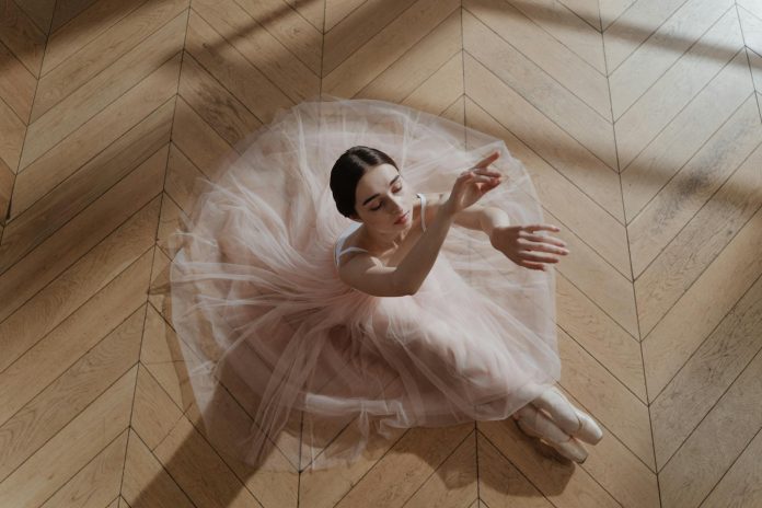 Woman in Pink Tutu Skirt Sitting on a Brown Wooden Floor